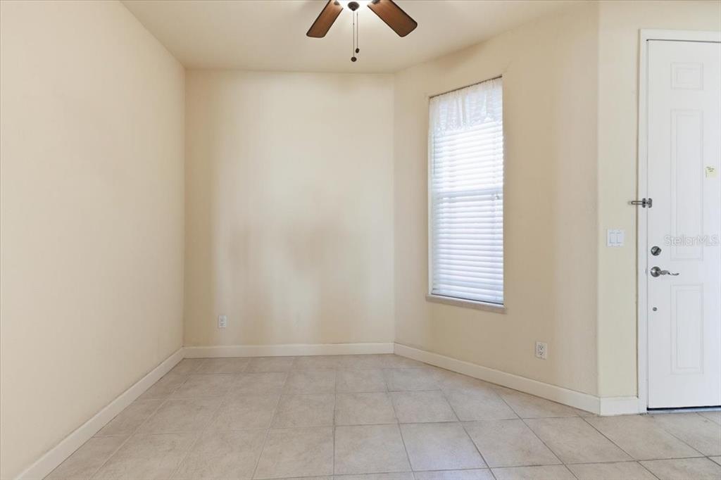 An empty room with beige walls, tile flooring, a ceiling fan, and a white door — 10045 LINKS LANE UNIT 203, ROTONDA WEST, FL