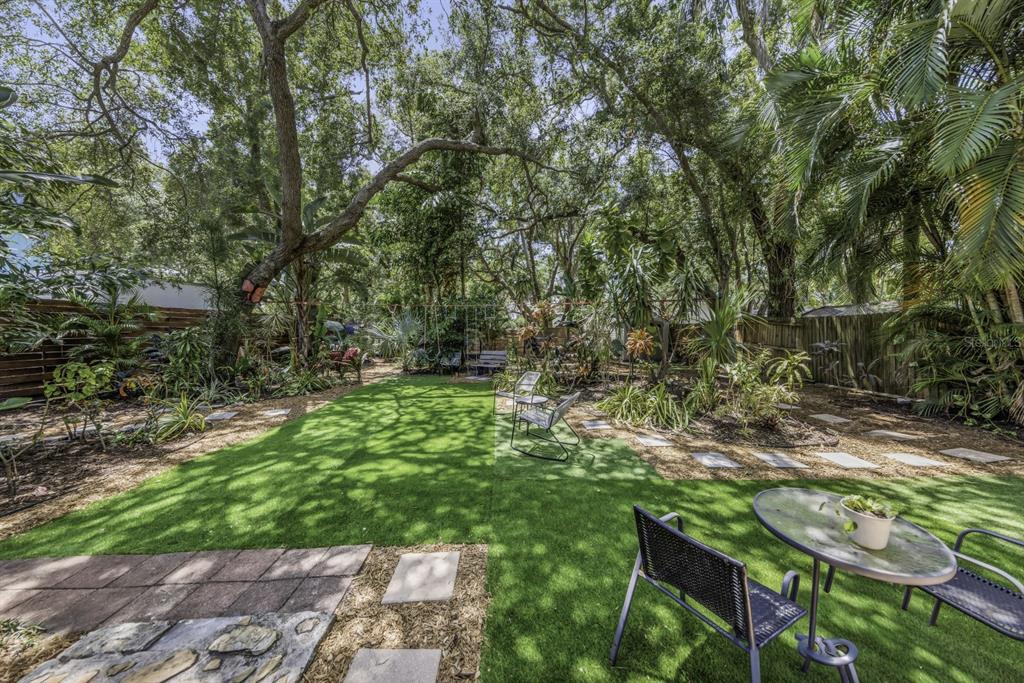 A backyard features a patch of artificial turf, patio furniture, and mature trees — 416 N WASHINGTON AVENUE, CLEARWATER, FL