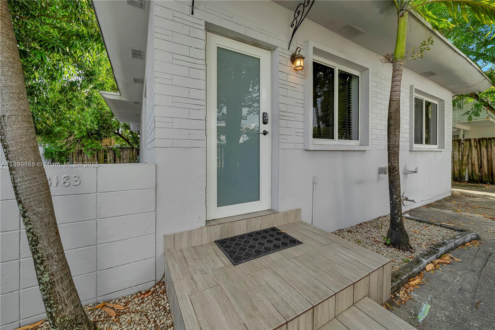 The exterior of a white brick building features a glass-paneled door and tiled steps — 3181 NW 5th Ave, Miami FL 33127, MIAMI, FL