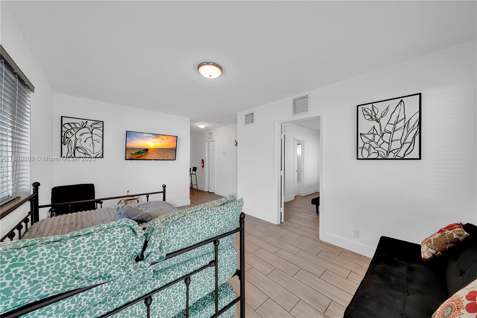 A bedroom features a metal-framed bed, a black sofa, and white walls with tile flooring — 3181 NW 5th Ave, Miami FL 33127, MIAMI, FL