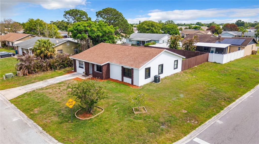 An aerial view of a white single-story house with a brown roof on a corner lot — 107 IGUALA DRIVE, KISSIMMEE, FL