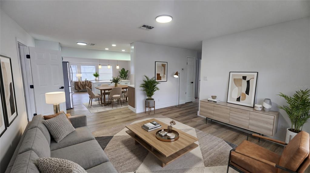 A living room with light wood flooring opens into a dining area and kitchen — 107 IGUALA DRIVE, KISSIMMEE, FL