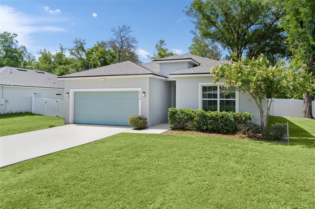 A single-story house with a light gray exterior, a light blue garage door, and a lawn — 8578 SE 164TH PLACE, SUMMERFIELD, FL