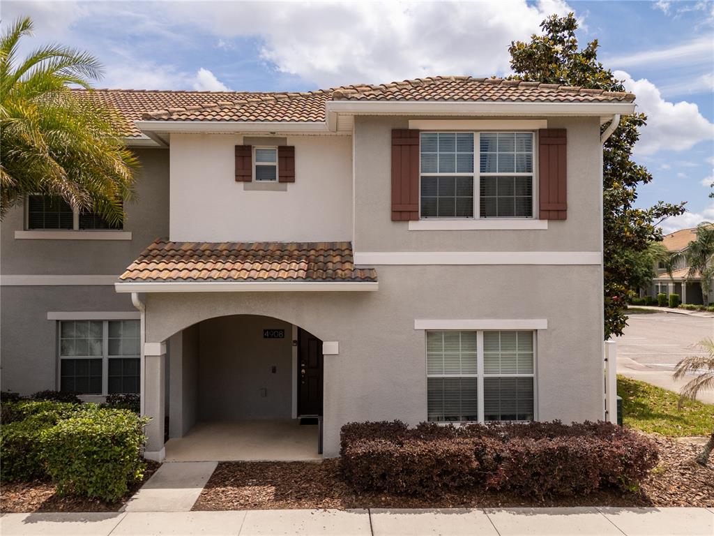 A two-story townhouse with a stucco exterior, brown shutters, and a covered entryway — 4908 CLOCK TOWER DRIVE, KISSIMMEE, FL