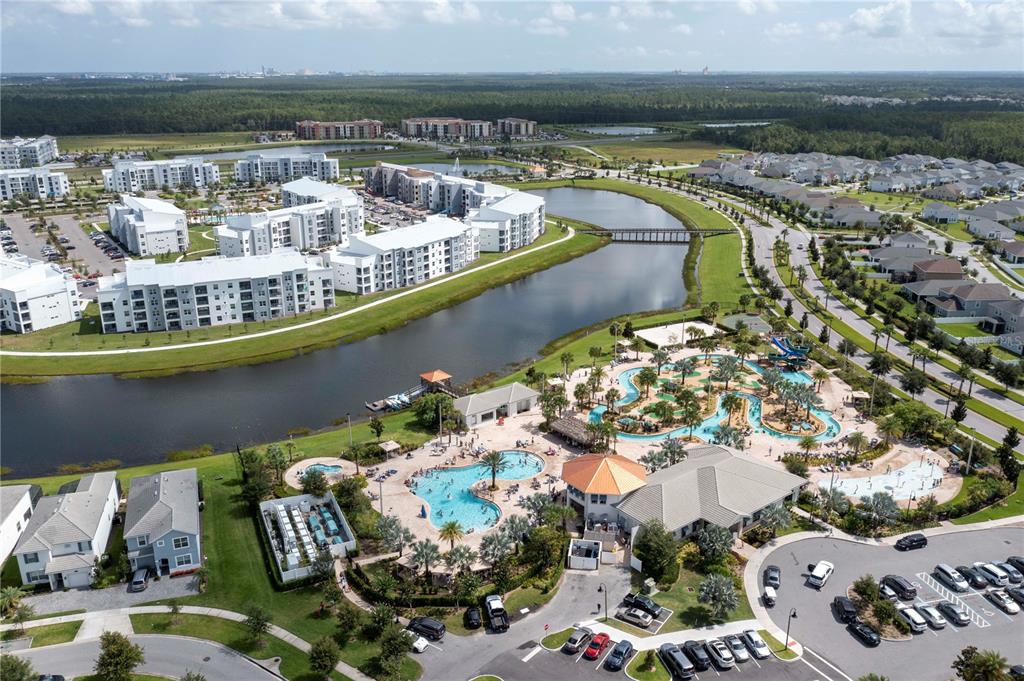 An aerial view shows a residential community with apartment buildings, a large pool, and parking — 4908 CLOCK TOWER DRIVE, KISSIMMEE, FL