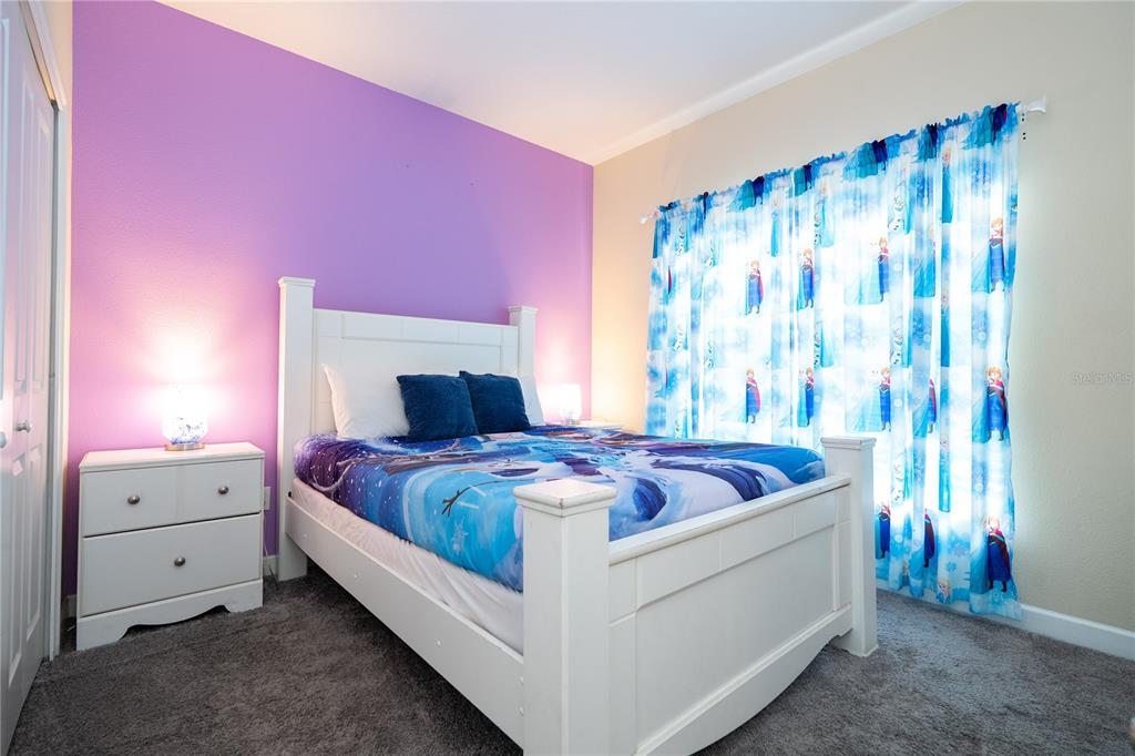 A bedroom features a white bed frame, purple accent wall, and Frozen-themed bedding and curtains — 4908 CLOCK TOWER DRIVE, KISSIMMEE, FL