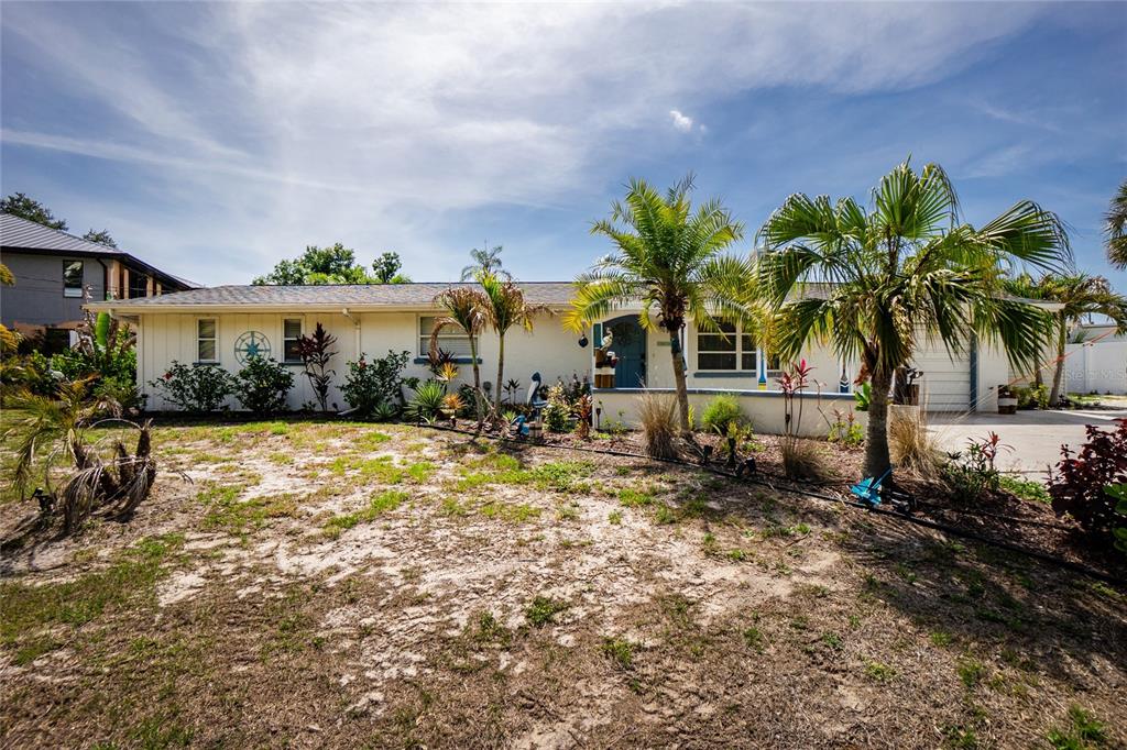 A single-story house with a light-colored exterior, palm trees, and a sandy front yard — 625 SANDPIPER LANE, NOKOMIS, FL