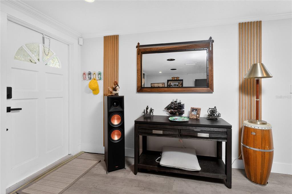 An entryway features a white door, wood-slat wall accents, a dark console table, and a speaker — 625 SANDPIPER LANE, NOKOMIS, FL