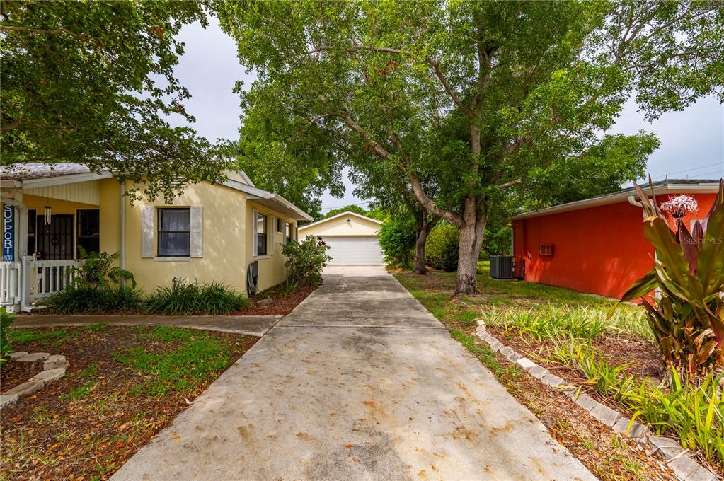 A concrete driveway leads to a detached garage between a yellow house and a red building — 311 GILL STREET, PUNTA GORDA, FL