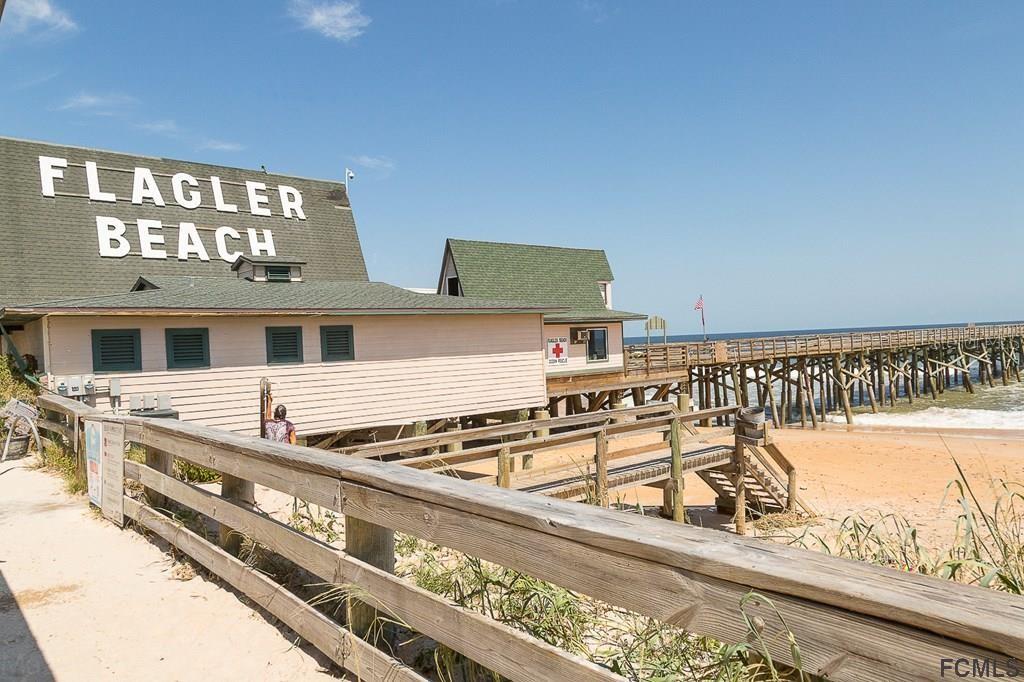 A wooden building with a Flagler Beach sign stands beside a pier on the beach — 70 BUTTERMILL DRIVE, PALM COAST, FL