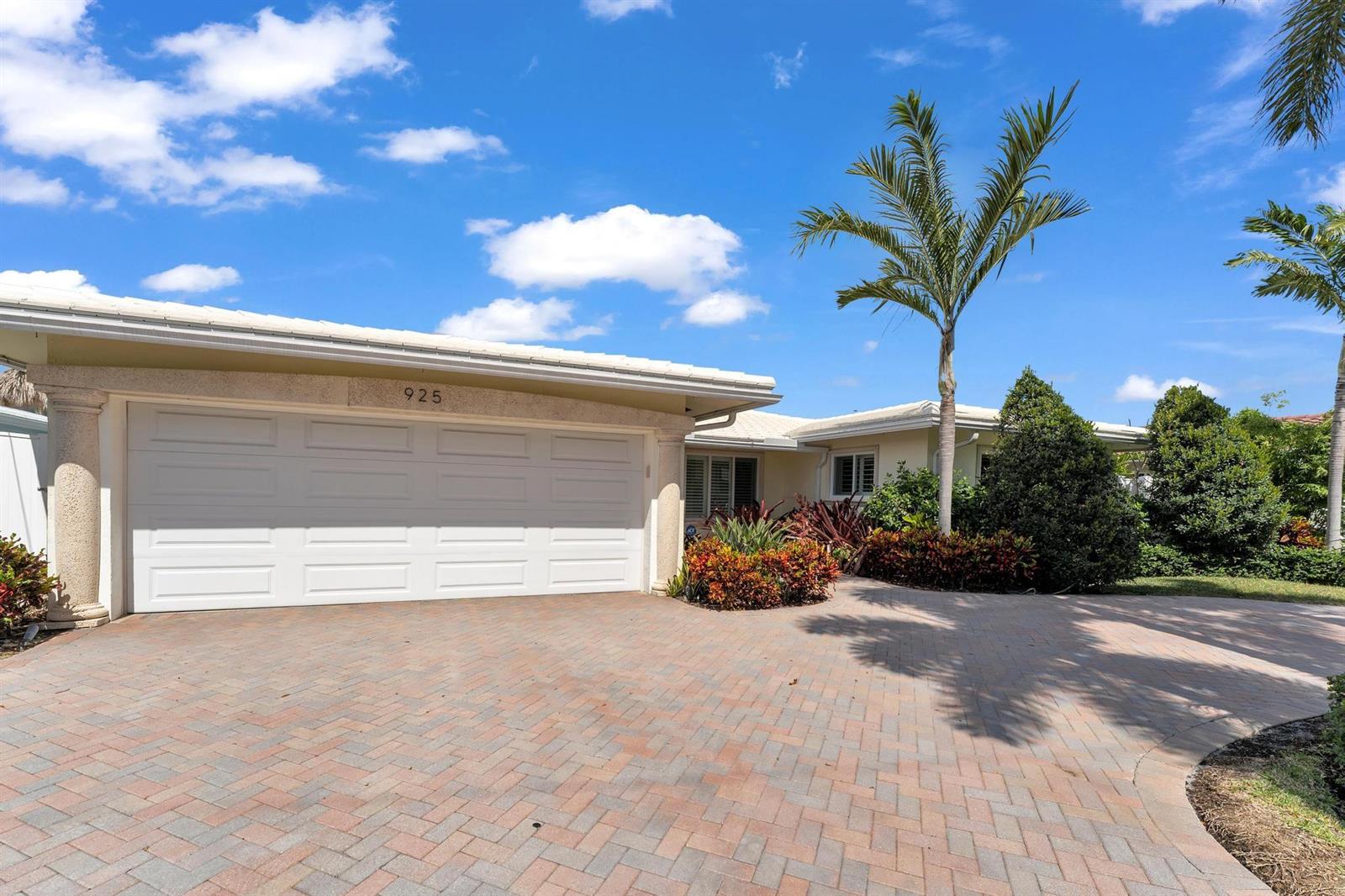 A single-story house with a white garage door, stone columns, and a brick paver driveway — 925 SE 10th Street, Pompano Beach FL 33060, POMPANO BEACH, FL