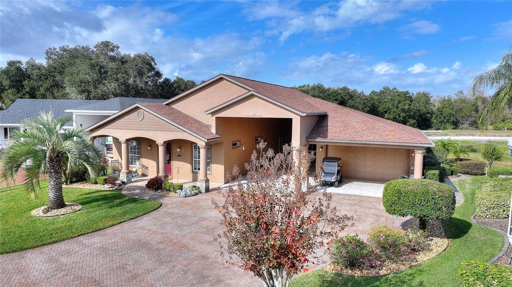 A tan house with a brick driveway, a covered entryway, and an attached garage — 370 MEANDERING WAY, POLK CITY, FL