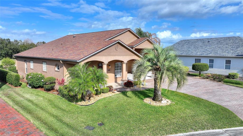 A tan single-story house with a brown shingled roof and a brick paver driveway — 370 MEANDERING WAY, POLK CITY, FL