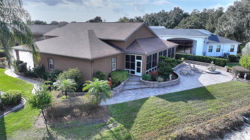 An aerial view of a brown house with a screened porch and a paved patio — 370 MEANDERING WAY, POLK CITY, FL