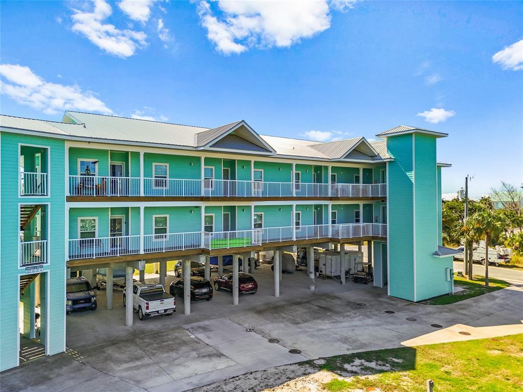 A three-story teal building on stilts features white railings and a covered parking area — 502 MAIN STREET UNIT 112, HORSESHOE BEACH, FL