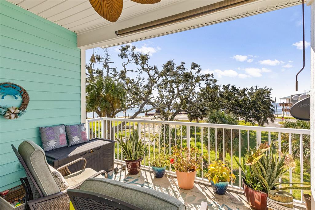 A balcony with outdoor furniture, potted plants, and a view of trees and water — 502 MAIN STREET UNIT 112, HORSESHOE BEACH, FL