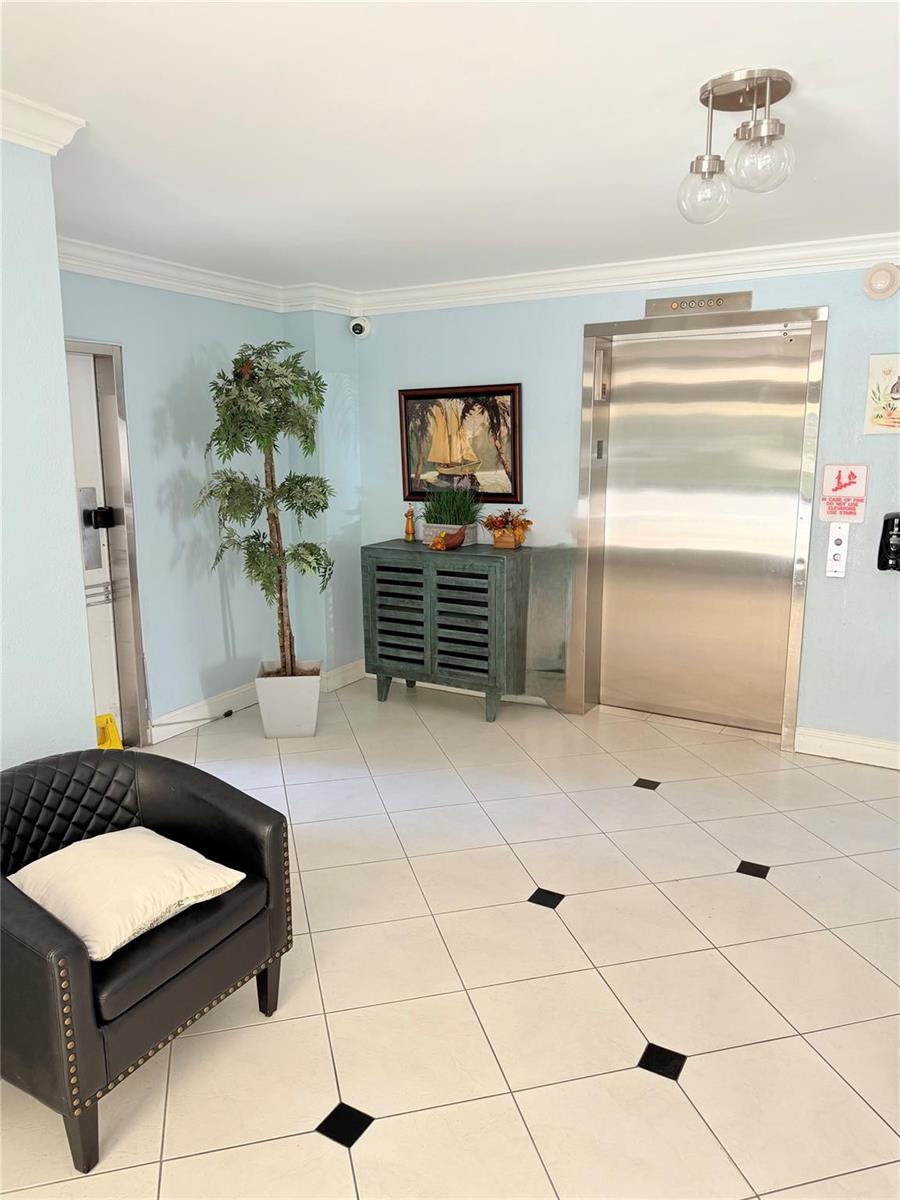 A lobby features a black armchair, a potted plant, a cabinet, and a stainless elevator — 2801 N Palm Aire Drive # 604, Pompano Beach FL 33069, POMPANO BEACH, FL