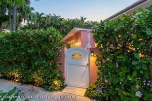 A white arched gate leads to a pink building surrounded by lush green hedges — 142 Peruvian Avenue # 1020, Palm Beach FL 33480, PALM BEACH, FL