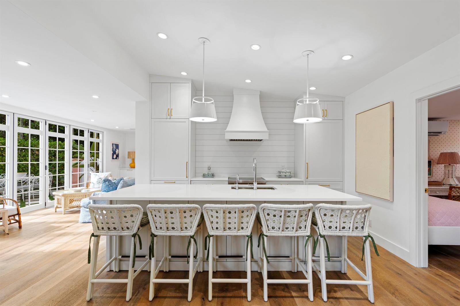 A bright kitchen features a large white island with five woven stools and shiplap walls — 142 Peruvian Avenue # 1020, Palm Beach FL 33480, PALM BEACH, FL
