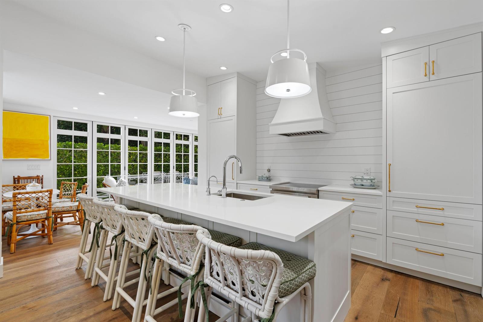 A bright kitchen features a white island with bar stools, shiplap walls, and gold hardware — 142 Peruvian Avenue # 1020, Palm Beach FL 33480, PALM BEACH, FL