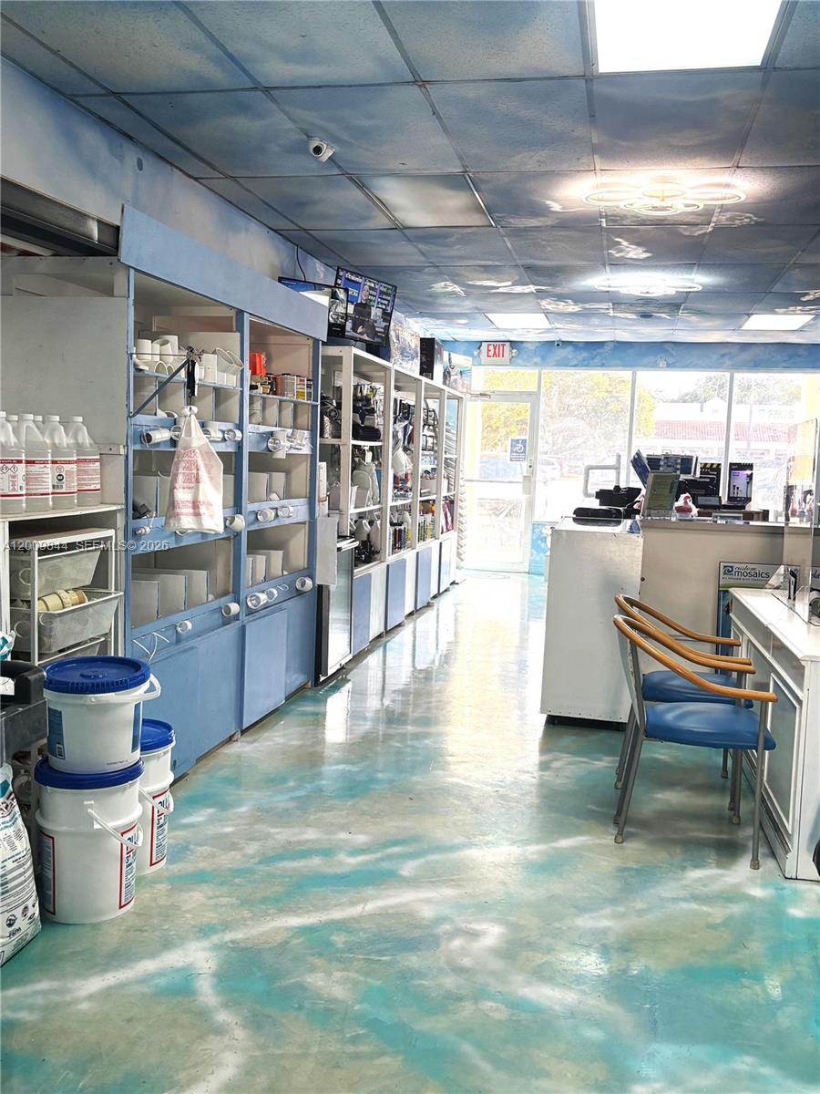 A retail store interior features blue-and-white cloud-patterned ceilings and floors with white shelving units — 82 SW 8, Miami FL 33144, MIAMI, FL