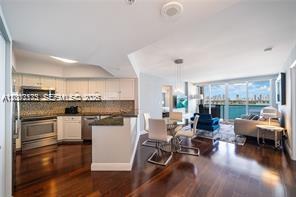 A modern open-concept kitchen and living area with dark hardwood floors and waterfront views — 1900 Sunset Harbour Dr # 1012, Miami Beach FL 33139, MIAMI BEACH, FL