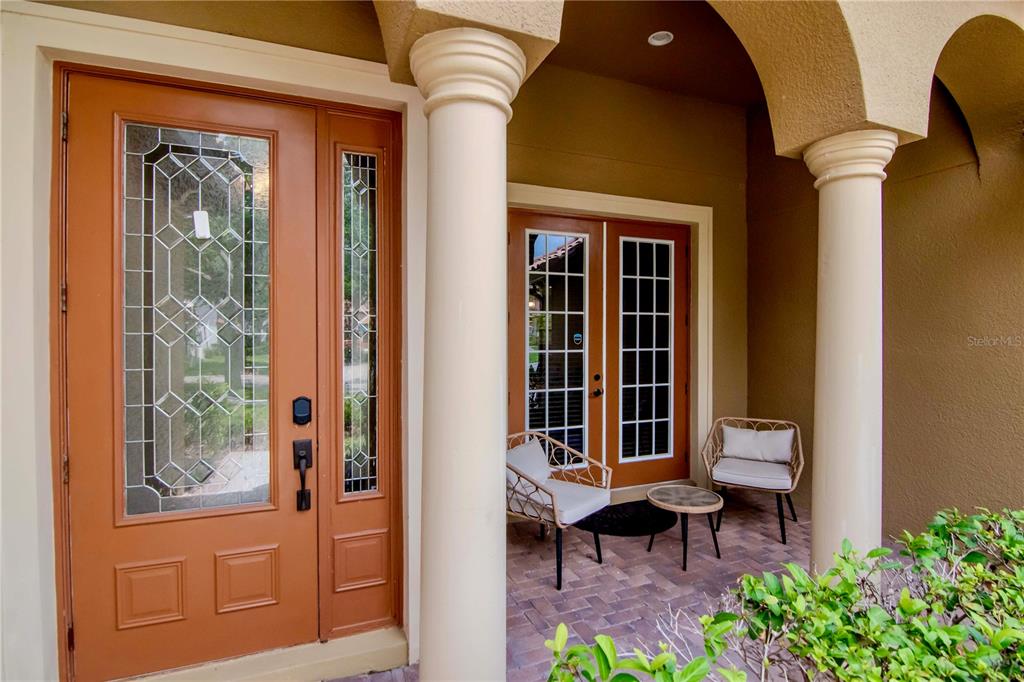 A covered entryway features a front door with glass panels, columns, and a small patio — 20110 POND SPRING WAY, TAMPA, FL
