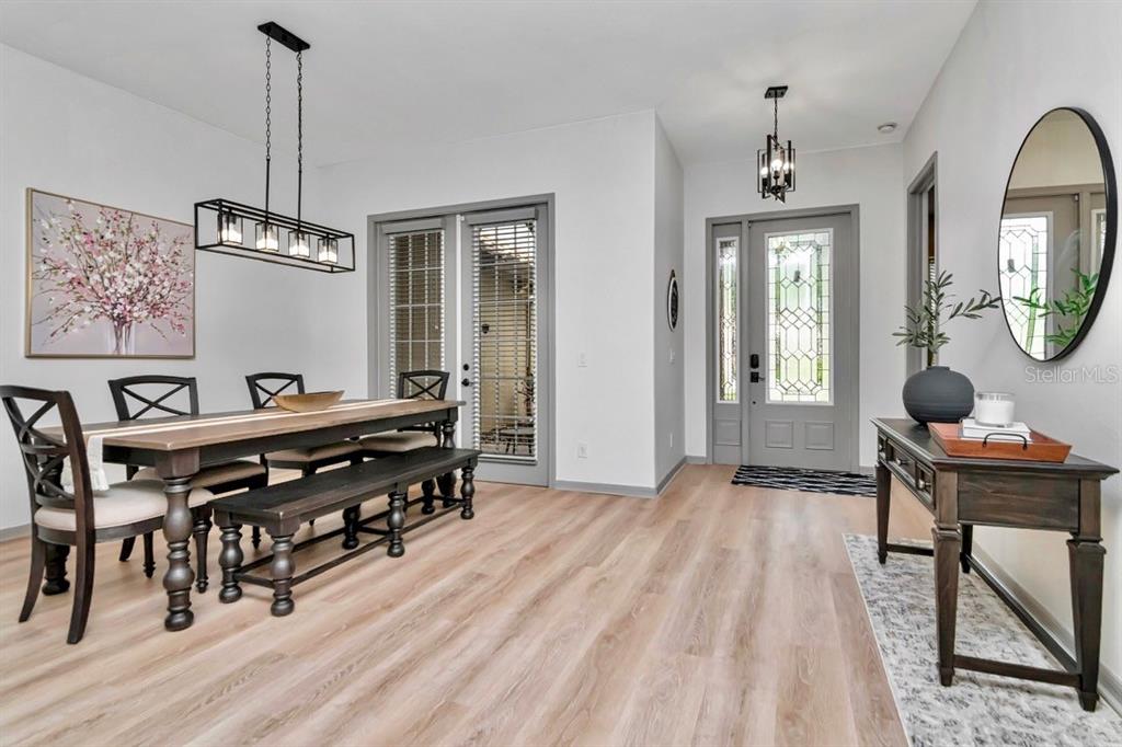 A dining area and entryway featuring wood-look flooring, a farmhouse table, and a glass-paneled door — 20110 POND SPRING WAY, TAMPA, FL