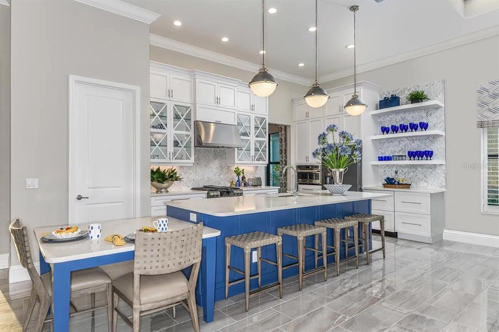 A kitchen features a blue island with bar stools, white cabinetry, and a dining table — 504 BOCELLI DRIVE, NORTH VENICE, FL