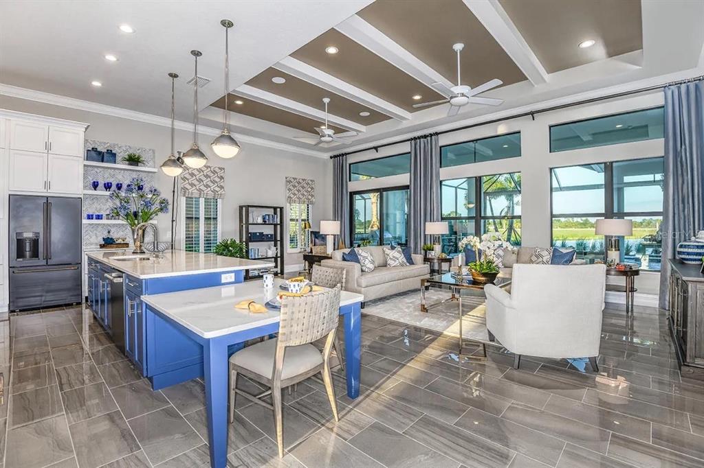 A modern open-concept kitchen and living area featuring a blue island, tile floors, and coffered ceilings — 504 BOCELLI DRIVE, NORTH VENICE, FL