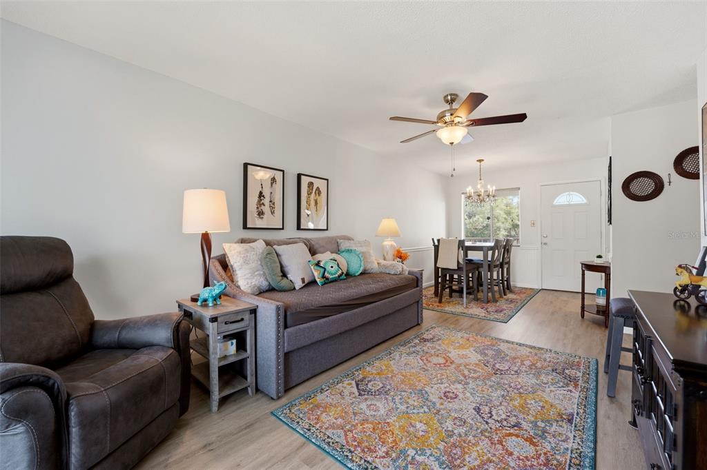 A living room features a sofa, a television, a ceiling fan, and a sliding glass door — 2545 FLAMINGO BOULEVARD UNIT L37, BRADENTON, FL