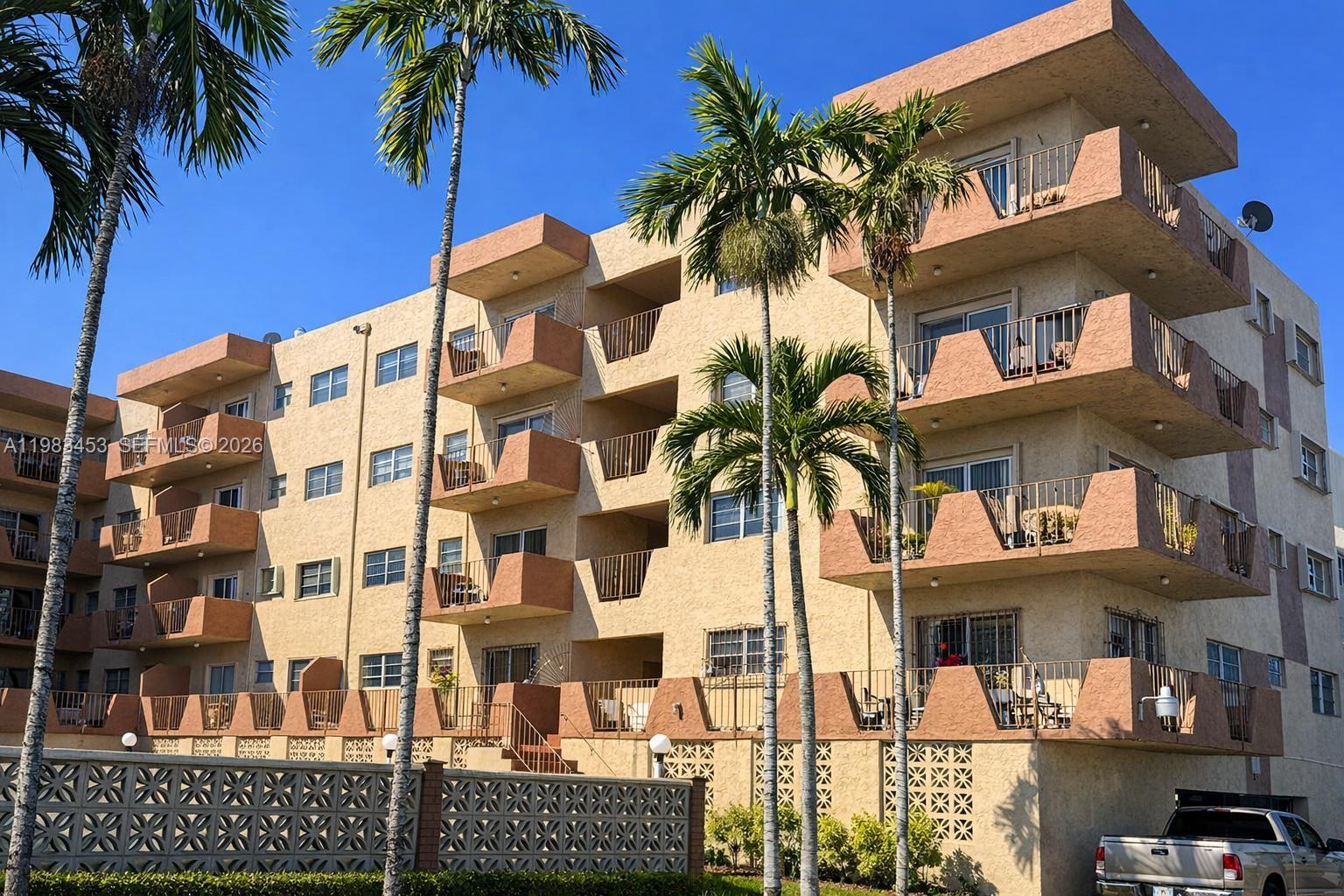 A multi-story apartment building features tan stucco walls, recessed balconies, and several palm trees — 1630 W 46th St # 514B, Hialeah FL 33012, HIALEAH, FL
