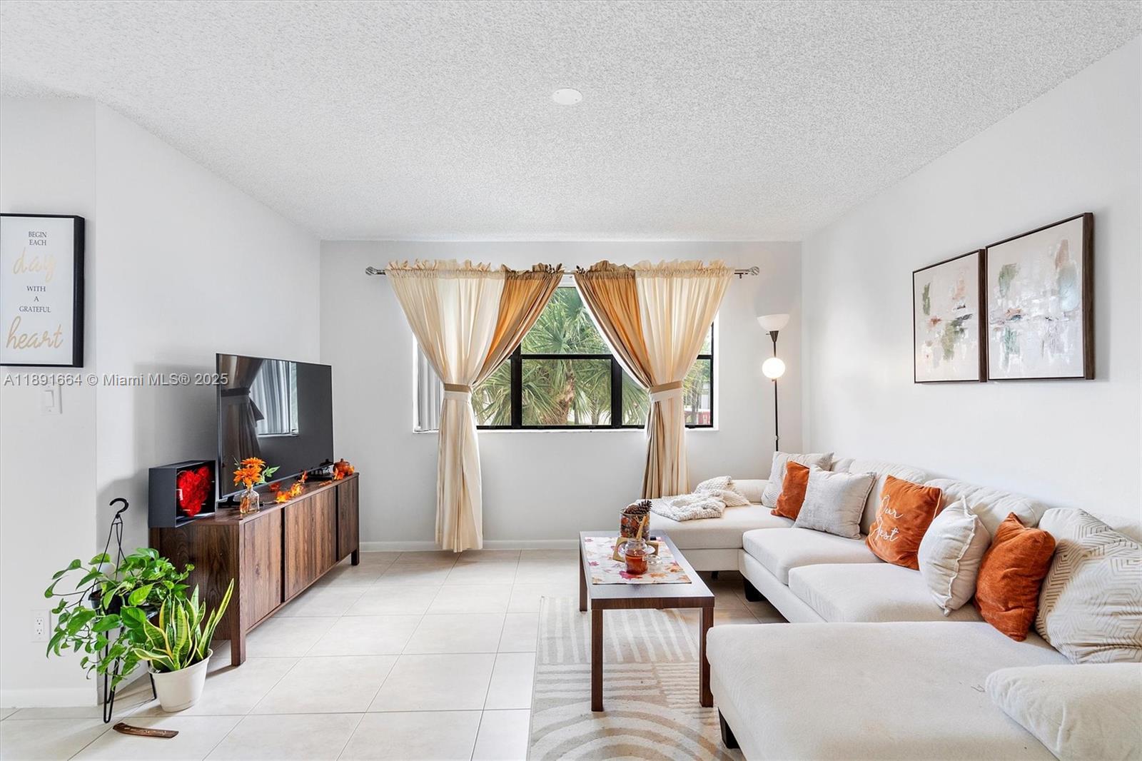 A living room features a white sectional sofa, a wood media console, and tile flooring — 510 S Park Rd # 10, Hollywood FL 33021, HOLLYWOOD, FL