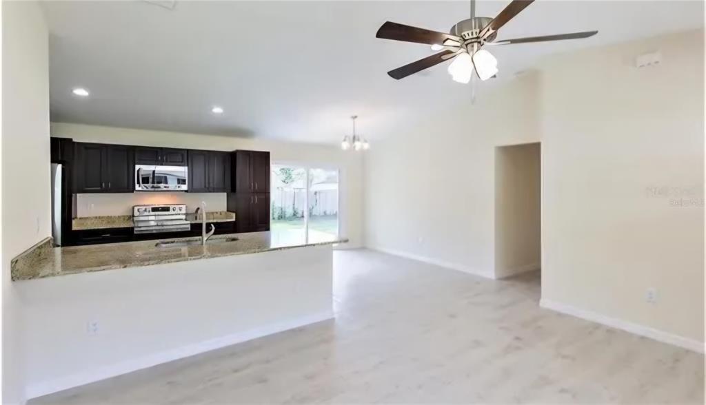 An open-concept kitchen with dark cabinets and granite countertops overlooks a spacious living area — 16295 SW 28TH COURT, OCALA, FL