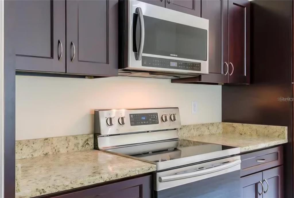 A kitchen features dark wood cabinets, stainless steel appliances, and light-colored granite countertops — 16295 SW 28TH COURT, OCALA, FL