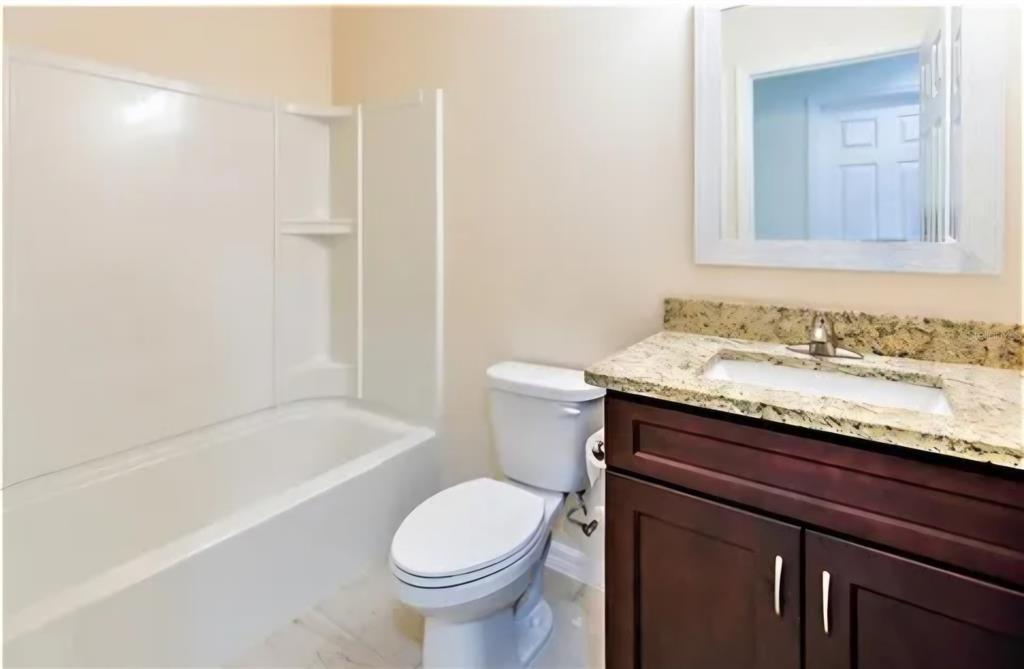 A bathroom features a white tub-shower combo, a toilet, and a dark wood vanity — 16295 SW 28TH COURT, OCALA, FL
