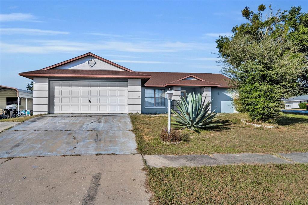 A single-story house with a two-car garage, a concrete driveway, and a large agave plant — 15215 SW 39TH CIRCLE, OCALA, FL