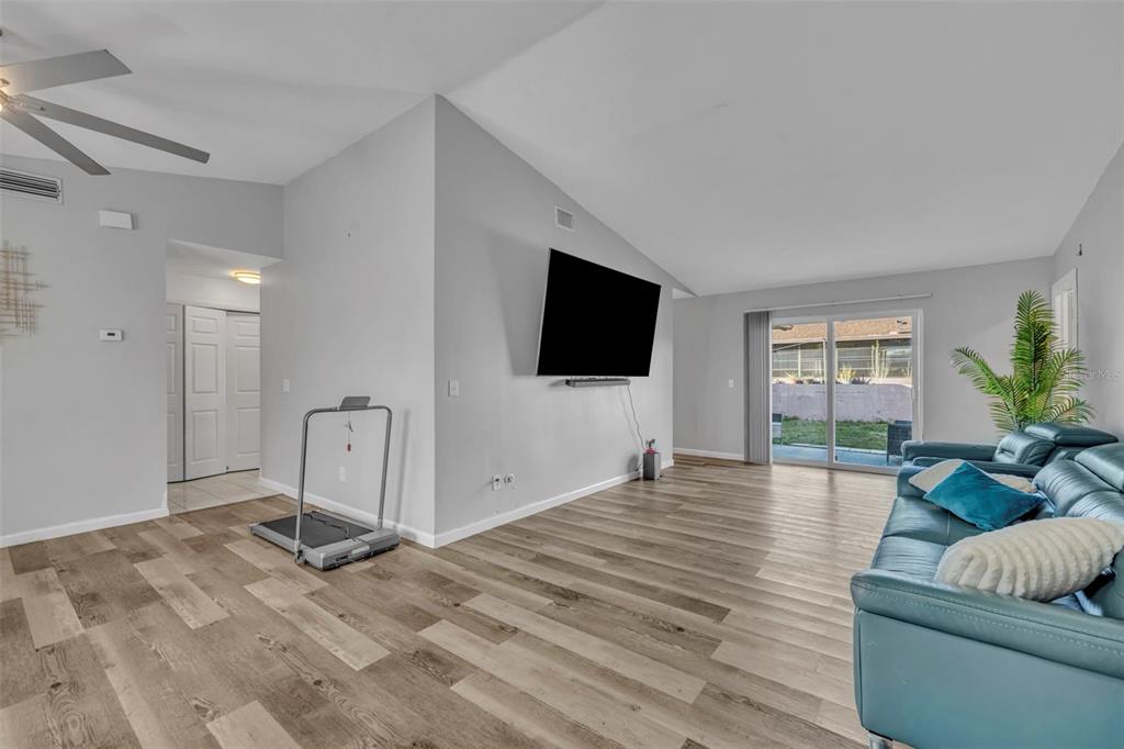 A living room features light wood-look flooring, a mounted television, and a blue leather sofa — 15215 SW 39TH CIRCLE, OCALA, FL