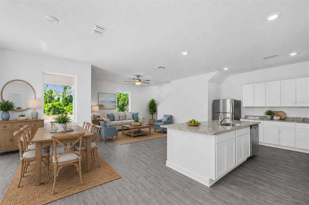 An open-concept living area features a kitchen with white cabinets, a dining table, and seating — 559 BAY LEAF DRIVE, POINCIANA, FL