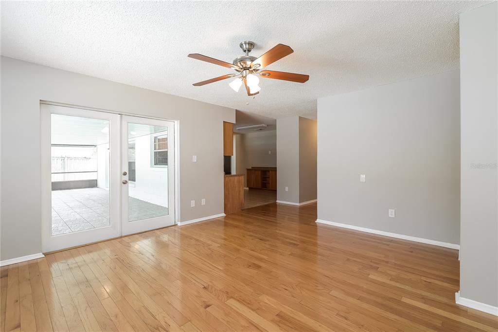 A living room with hardwood floors, a ceiling fan, and glass doors leading to a patio — 12013 CLOVE STREET, ORLANDO, FL