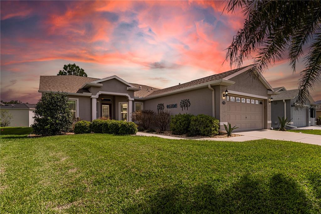 A single-story suburban house with a gray exterior, a two-car garage, and a manicured lawn — 27118 ROANOKE DRIVE, LEESBURG, FL