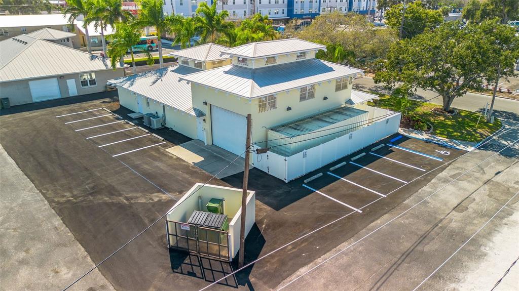 An aerial view shows a light yellow commercial building with a metal roof and parking — 525 8TH STREET W, BRADENTON, FL