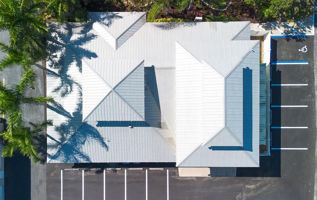 An aerial view shows a building with a metal roof surrounded by a parking lot — 525 8TH STREET W, BRADENTON, FL