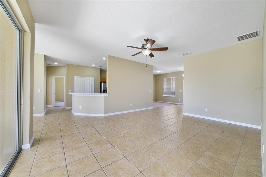 An open-concept living area features beige walls, tile flooring, and a ceiling fan — 243 WILDFLOWER ROAD, DAVENPORT, FL