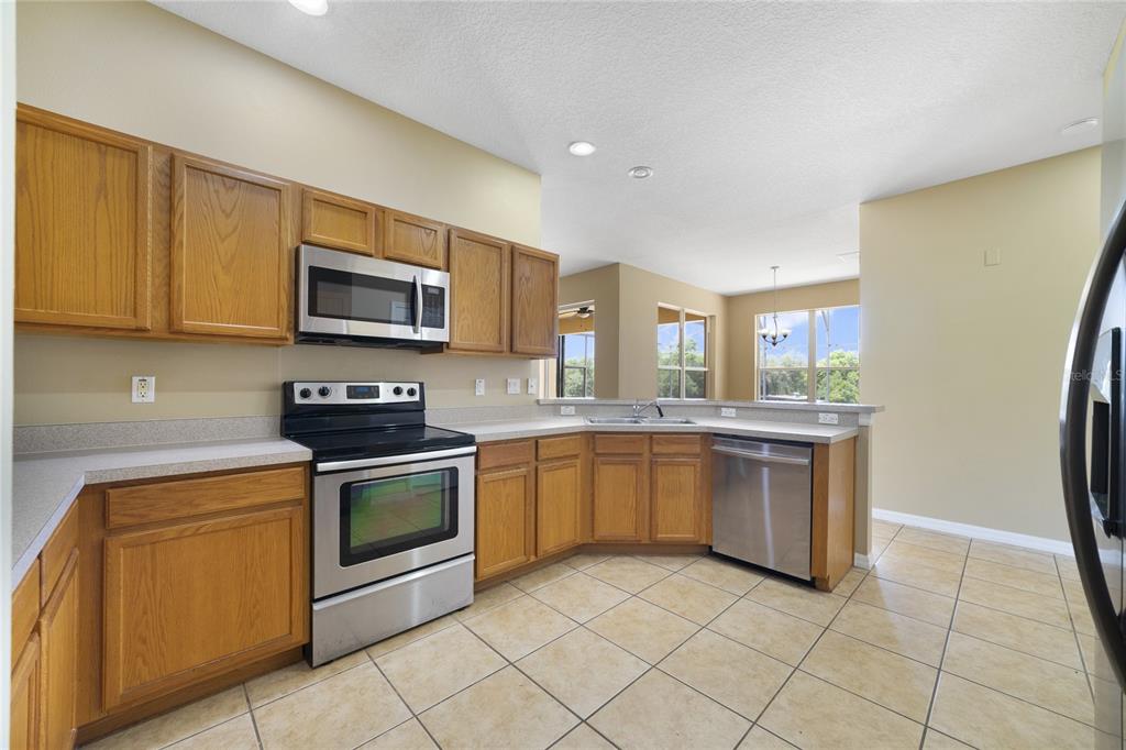 A kitchen with oak cabinets, stainless steel appliances, and tile flooring — 243 WILDFLOWER ROAD, DAVENPORT, FL