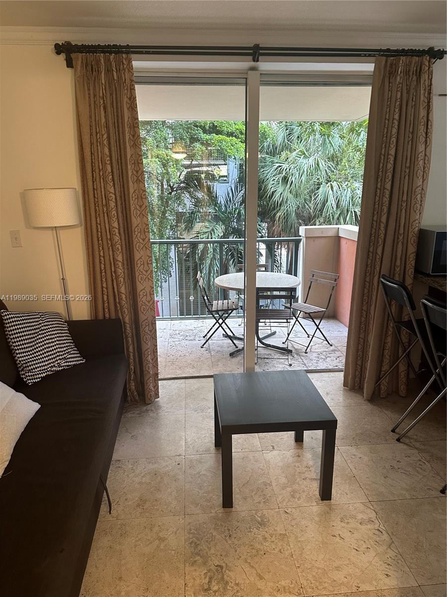A living room with tile floors opens to a balcony featuring a small bistro set — 2951 S Bayshore Dr # 417, Miami FL 33133, MIAMI, FL