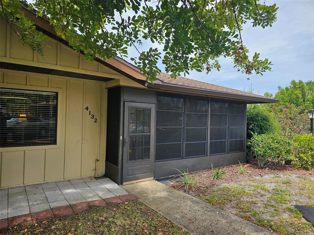 The exterior of a house features tan vertical siding, a screened-in porch, and a walkway — 4132 66TH STREET CIRCLE W, BRADENTON, FL