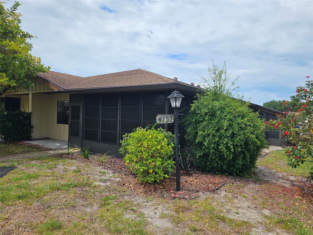 A single-story house features a screened-in porch, a brown shingled roof, and a front yard — 4132 66TH STREET CIRCLE W, BRADENTON, FL