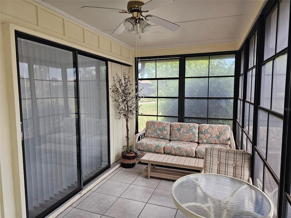 A sunroom features tiled flooring, a ceiling fan, sliding glass doors, and patio furniture — 4132 66TH STREET CIRCLE W, BRADENTON, FL