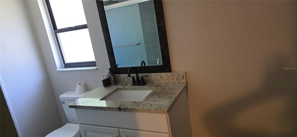 A bathroom features a granite vanity countertop, a white cabinet, and a framed mirror — 10021 CHERRY CREEK LANE, PORT RICHEY, FL